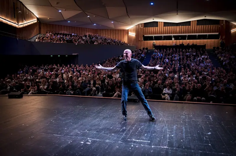 Marco “Monty” Montemagno a braccia aperte sul palco davanti a un teatro pieno